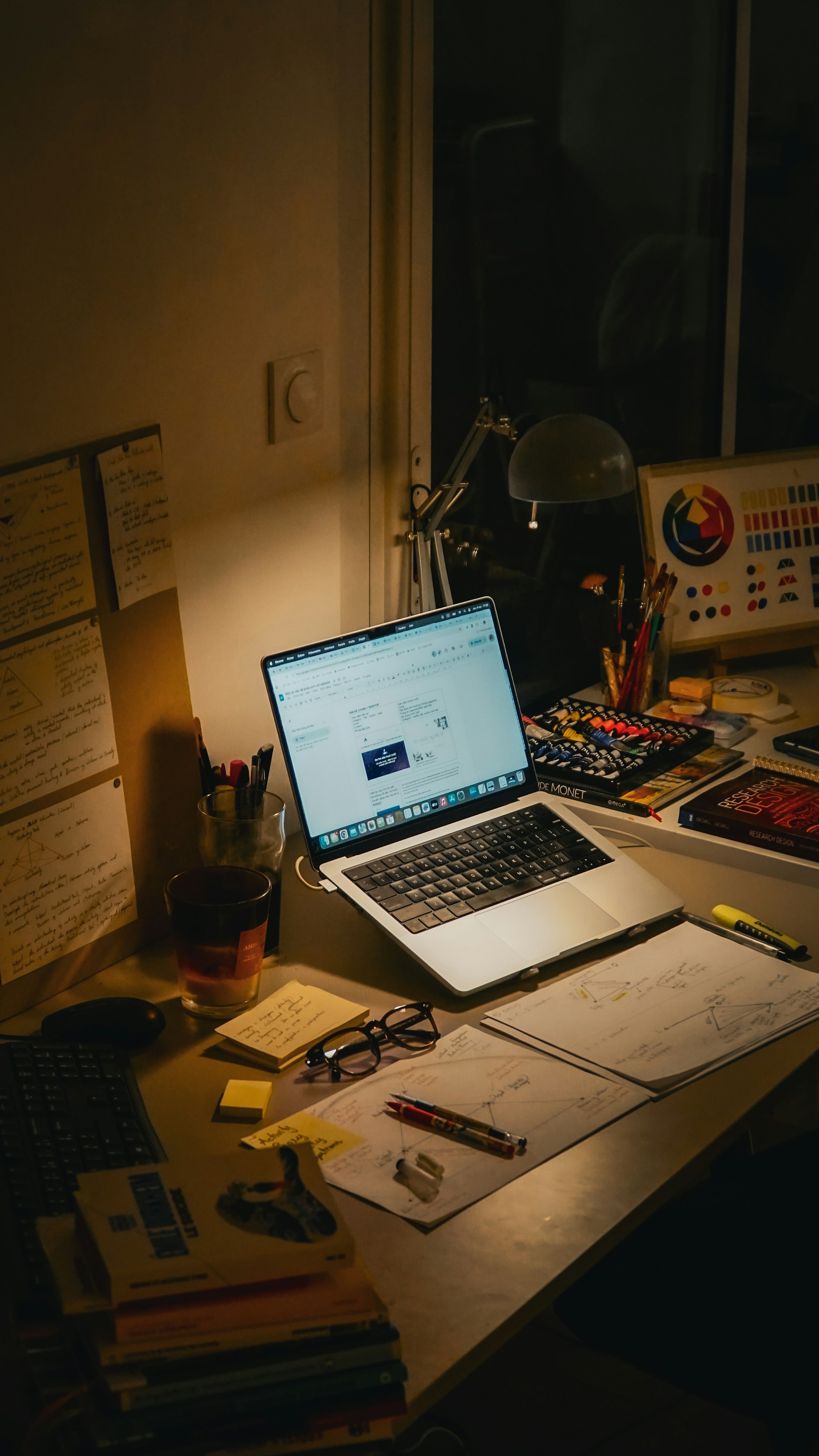 A desk with a laptop and textbooks at night